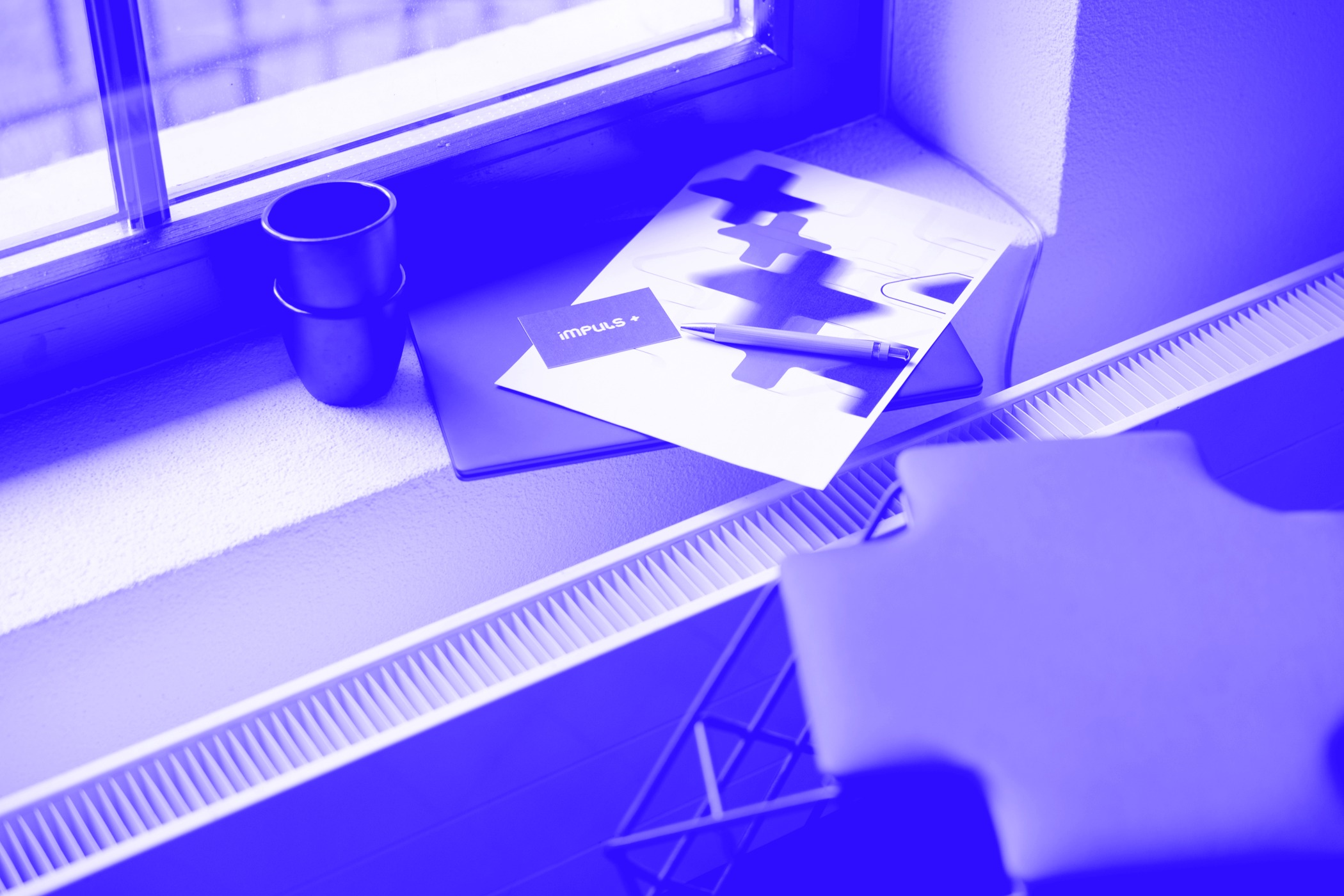 Detailshot von Laptop, Visitenkarte Impuls+ und Blatt mit Logo von Impuls Plus GmbH. Digitalisierung für mehr Zeit.